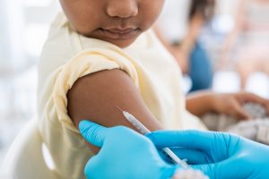 Immunisation. Protecting children from diseases. Close-up nurse in medical gloves giving injection to little patient. Brave boy getting a flu shot at doctor's office and looking at needle